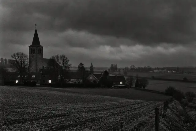 Illustration: Belgian farmland and a village church at night. AI-generated scene of the location, not evidence.