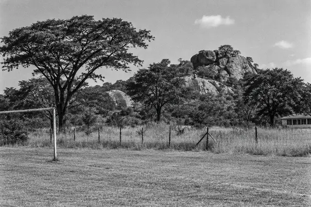 Illustration: an empty school playing field in rural Zimbabwe. AI-generated scene of the location, not evidence.
